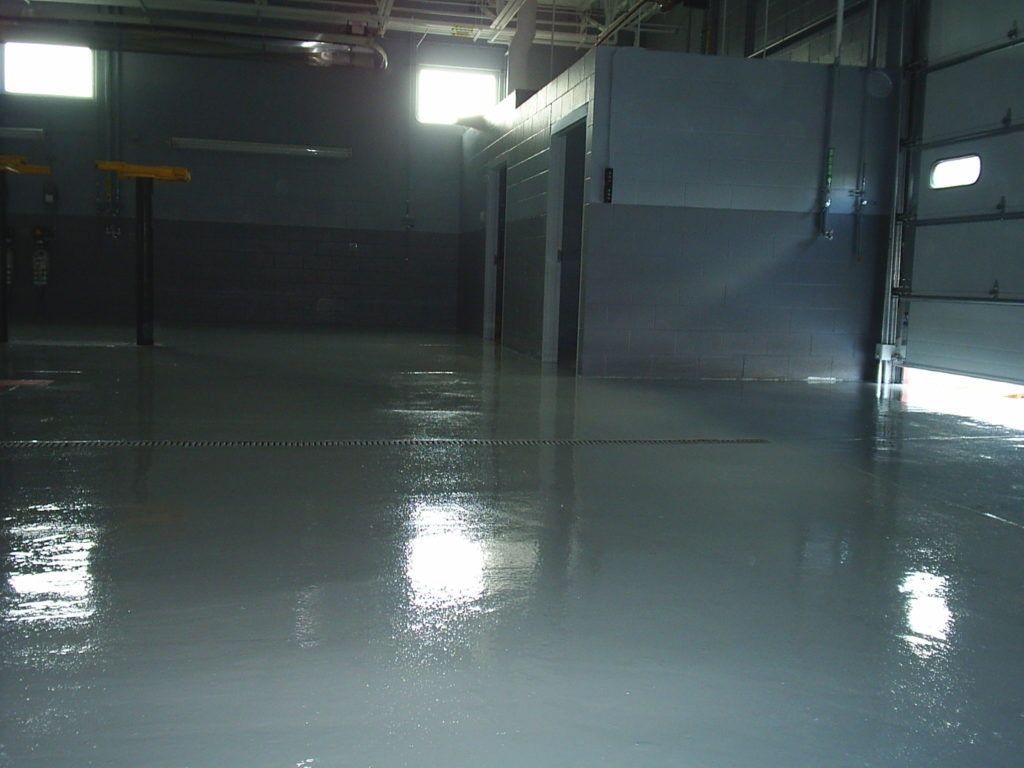 Dim empty industrial room with a glossy wet floor and bright overhead lights
