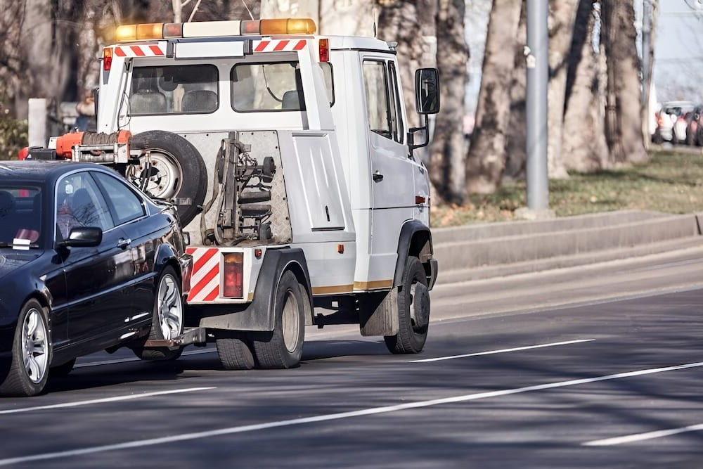 Tow Truck Towing a Black Car on a Road — Fulgi's South Coast Automotive and Dismantling in Wollongong, NSW