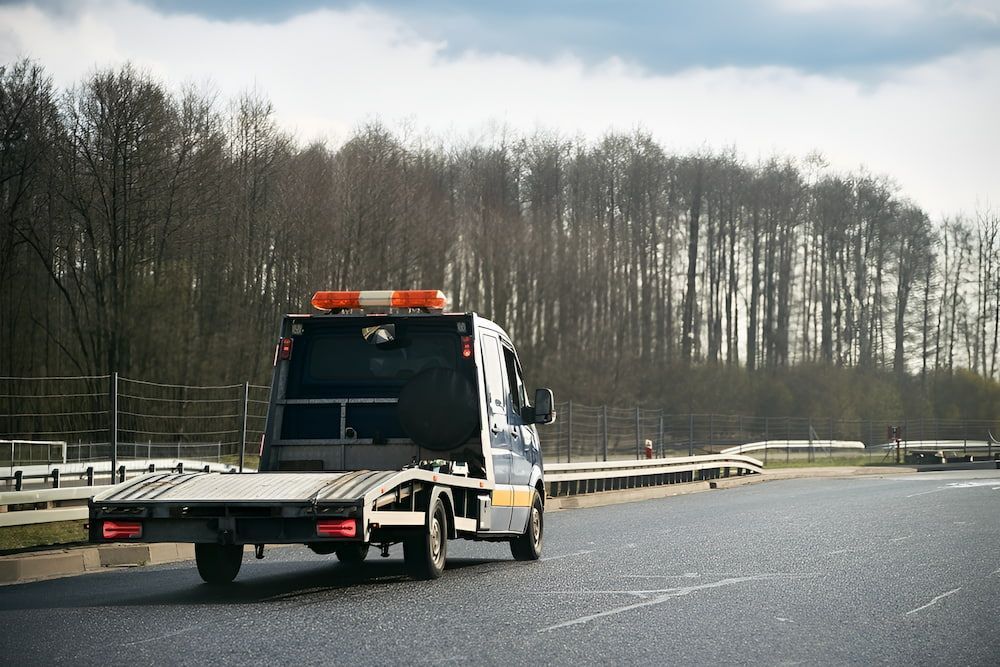 Tow Truck Driving on Asphalt Road, Trees — Fulgi's South Coast Automotive and Dismantling in Ulladulla, NSW