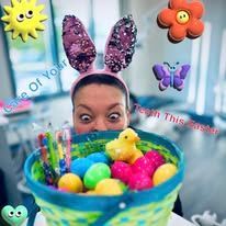Person wearing bunny ears holding Easter basket filled with eggs and toys.