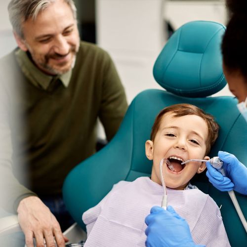 A little boy is getting his teeth examined by a dentist