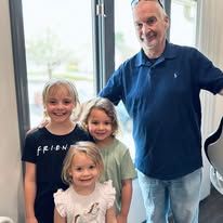A man and two little girls are posing for a picture in front of a window.