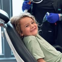 Young girl smiles in a dentist chair during a checkup.
