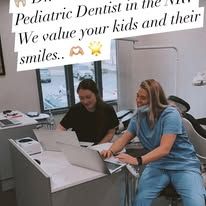 Two women working at desks with laptops in a dental office. One is smiling.