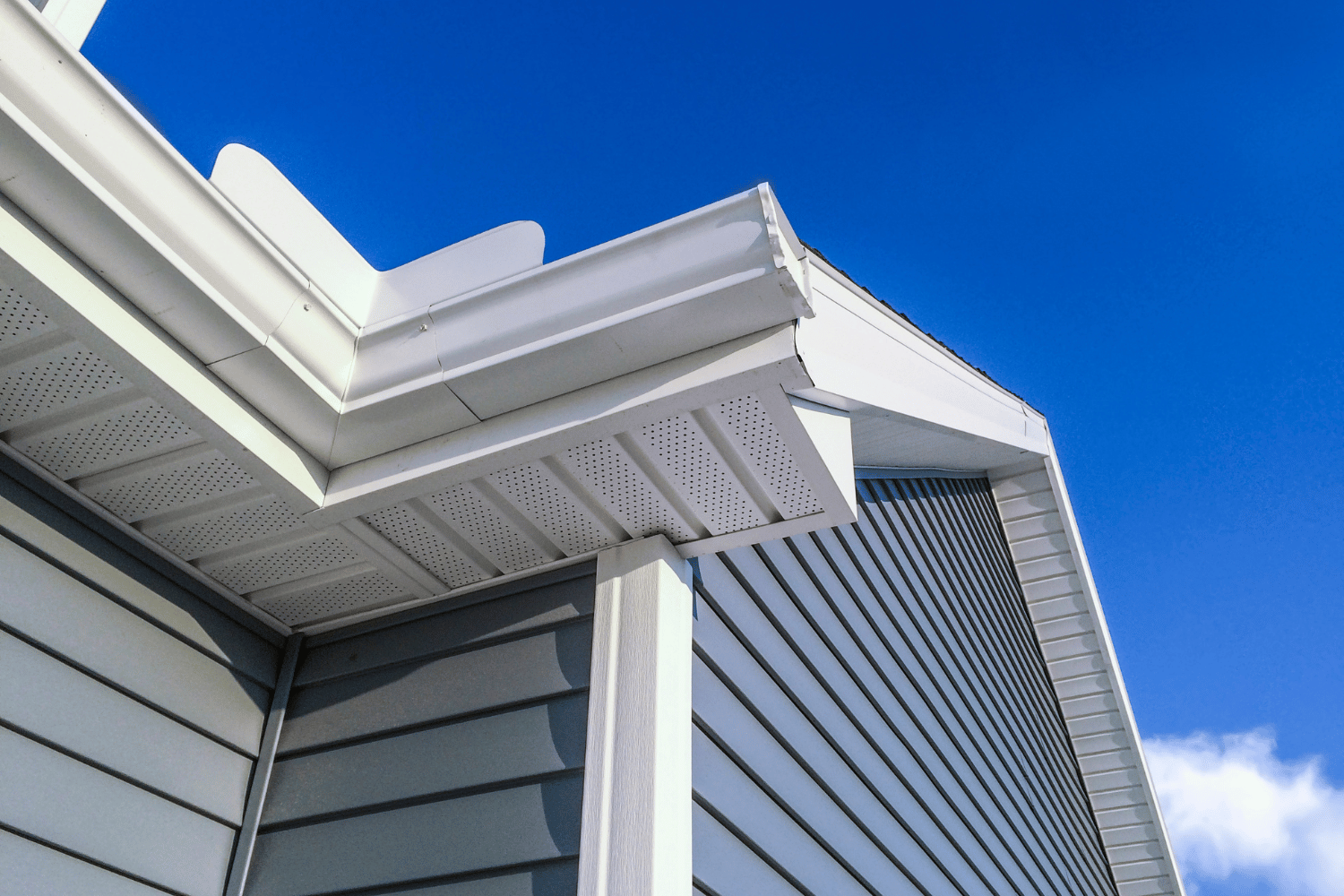 White house roof and gray siding against a bright blue sky