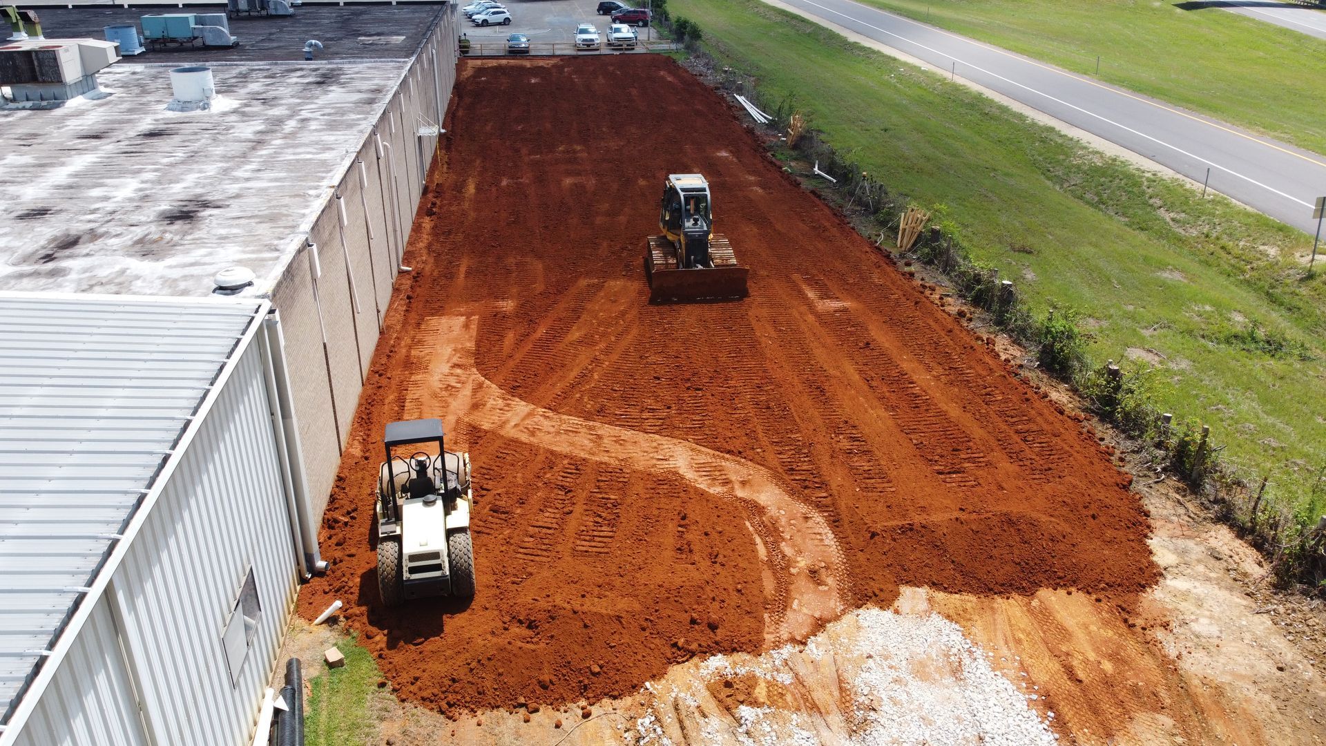 Two tractors are working on a large pile of dirt.