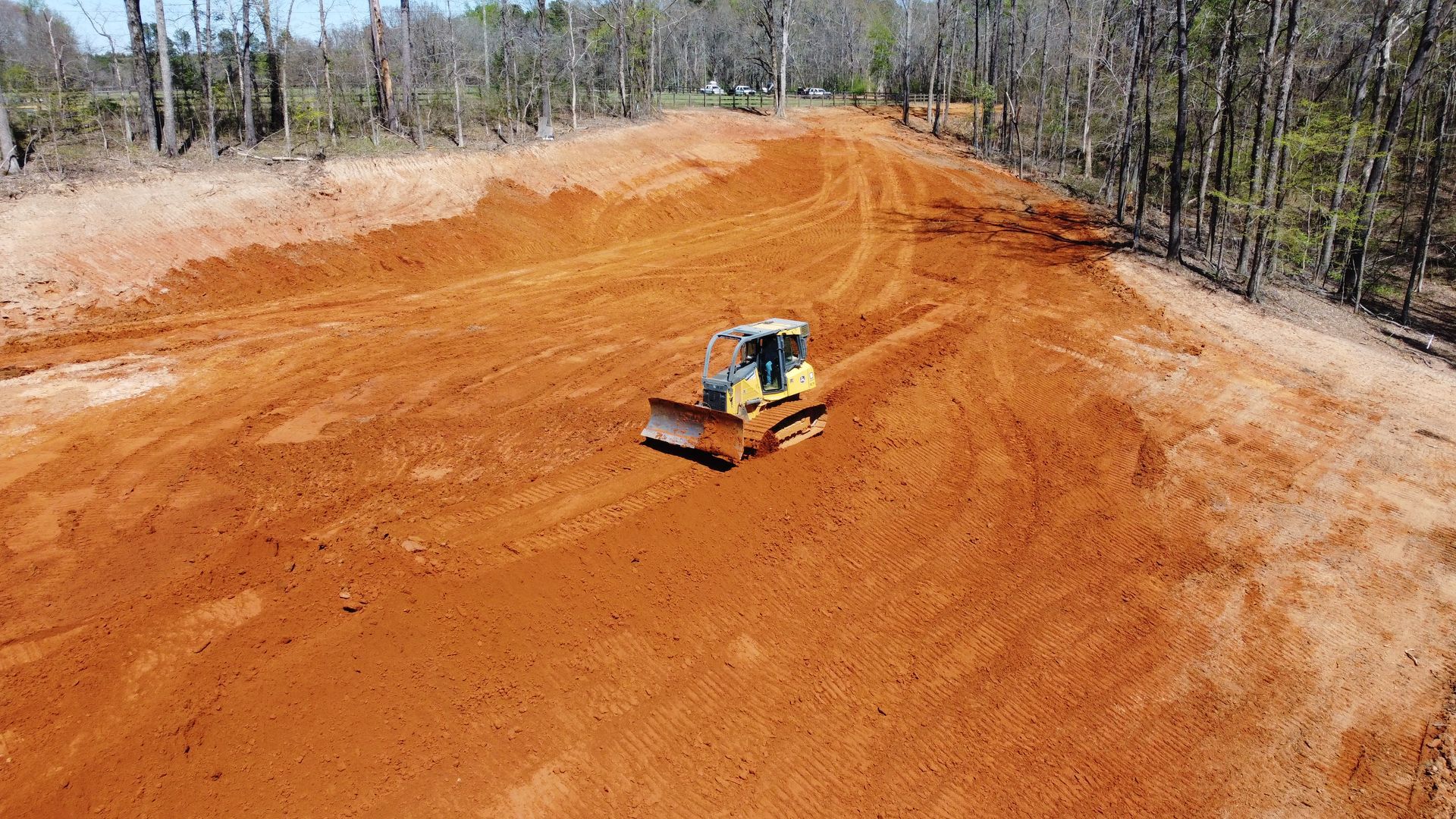 An aerial view of a bulldozer moving dirt on a dirt road.