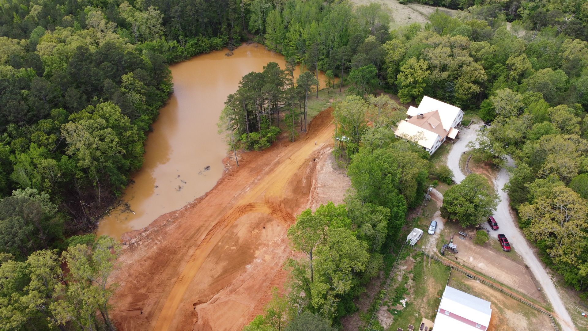 An aerial view of a house surrounded by trees and dirt.