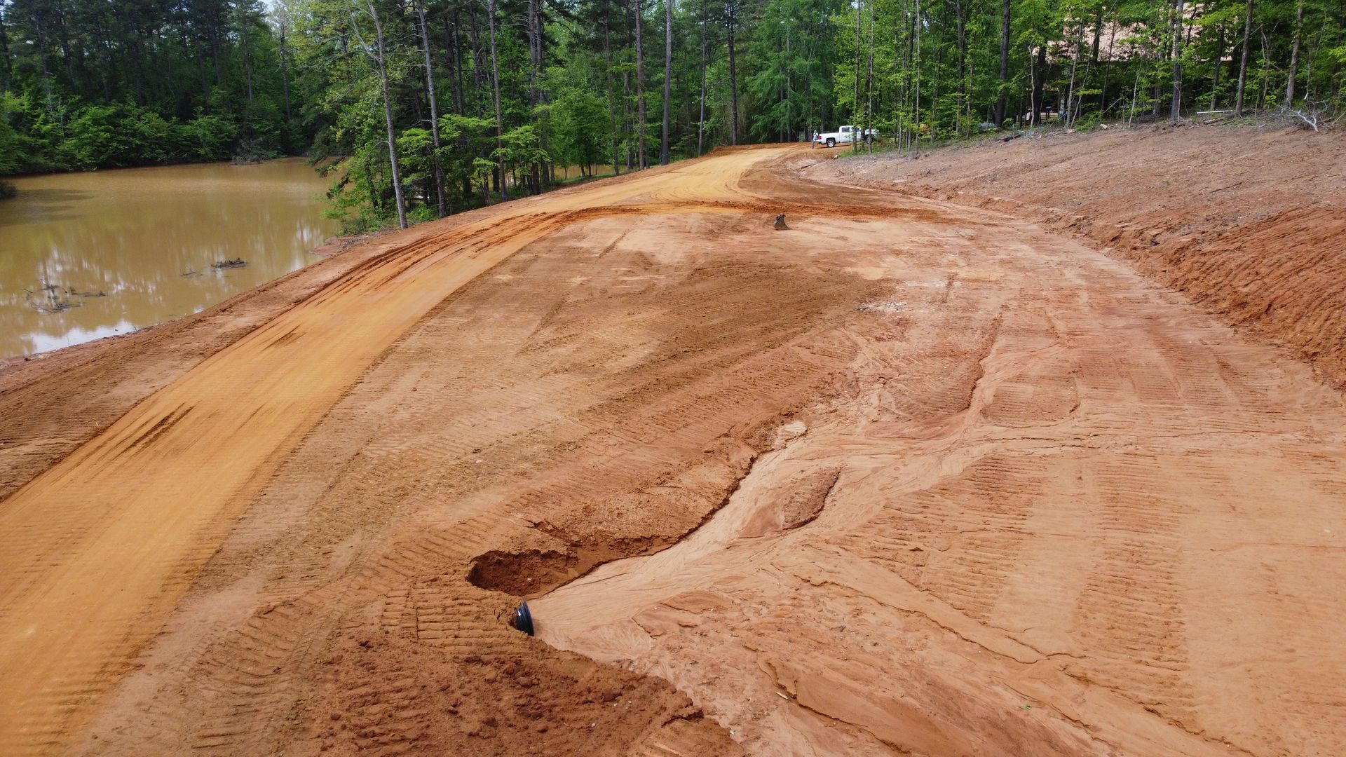A dirt road going through a flooded area next to a body of water.