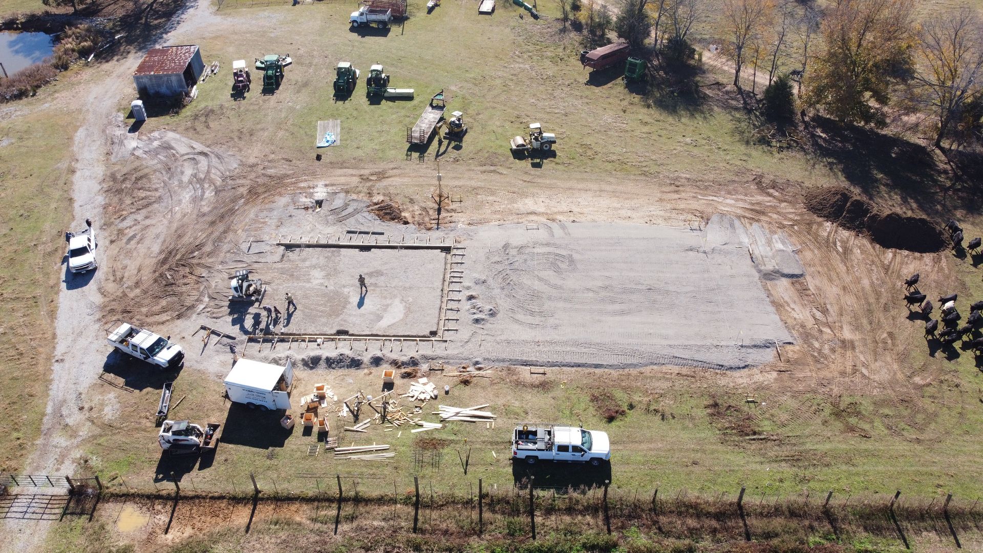 An aerial view of a construction site with trucks and a fence