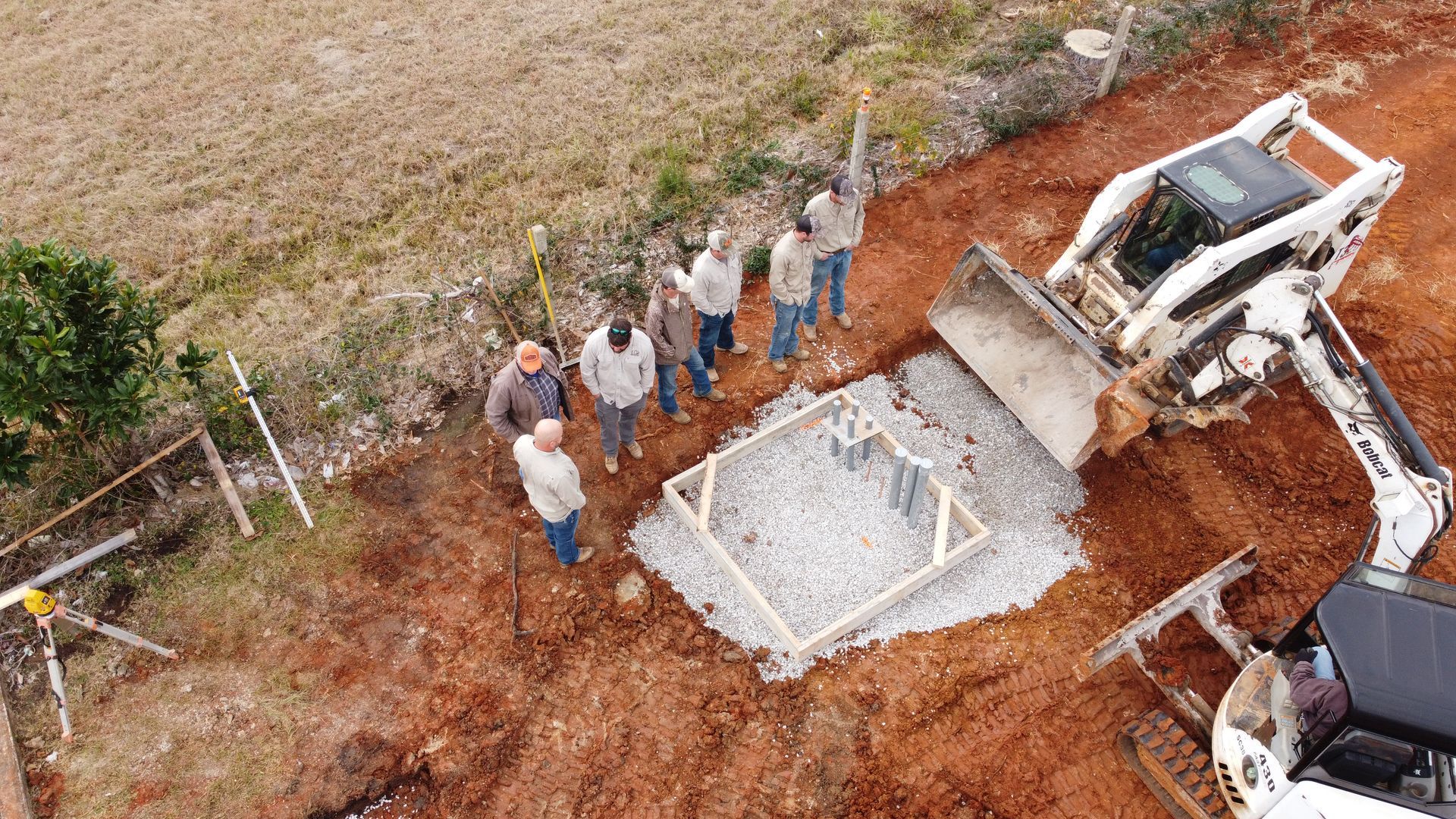 An aerial view of a group of people standing in the dirt next to a bulldozer.