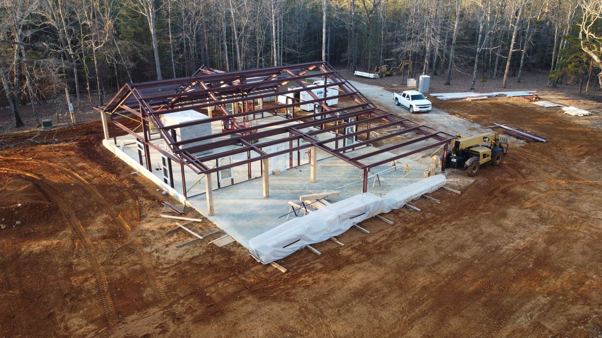 An aerial view of a building under construction in the middle of a dirt field.