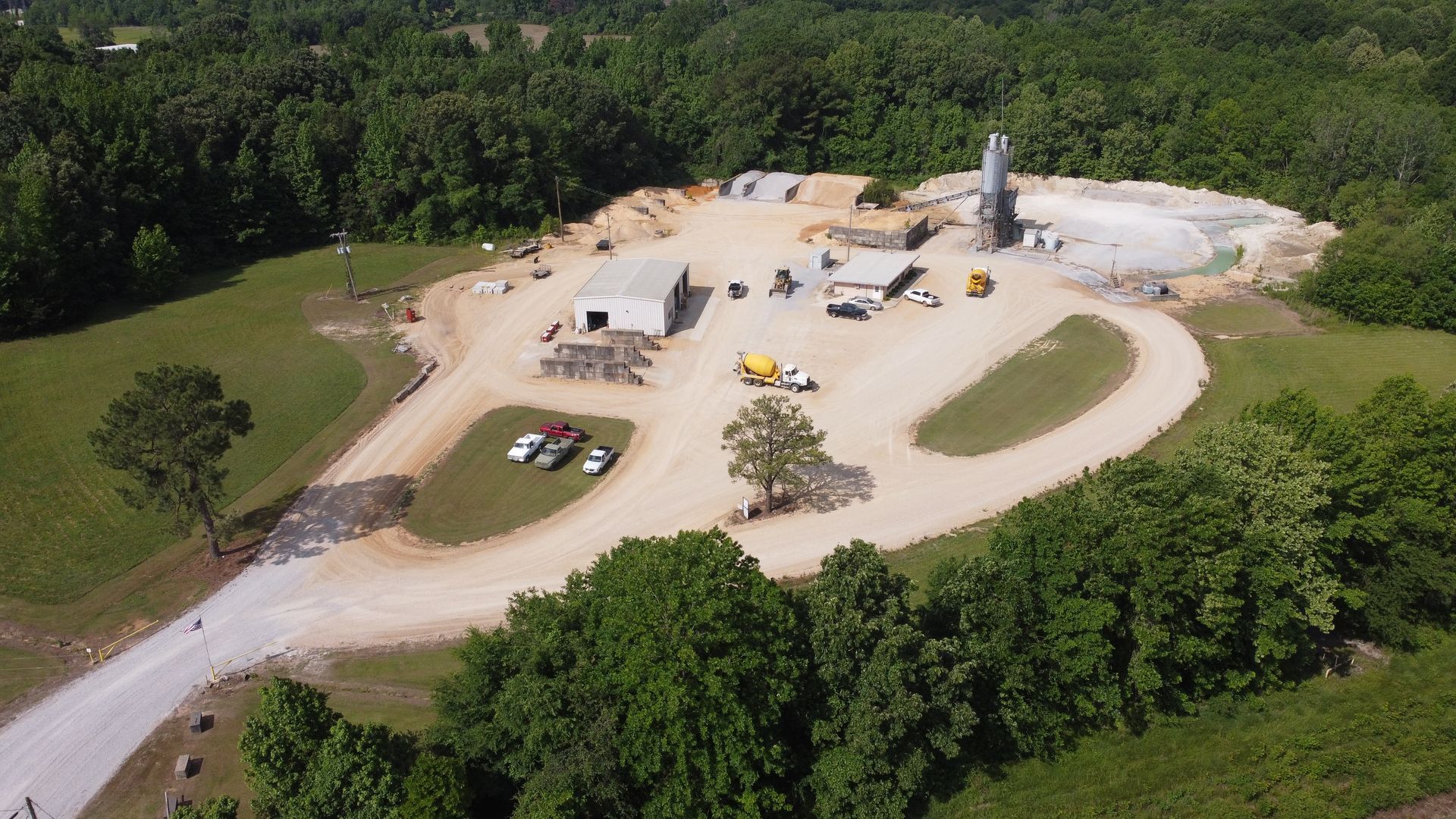 An aerial view of a dirt road surrounded by trees and buildings.