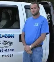 A man in a blue shirt is standing in front of a white truck.