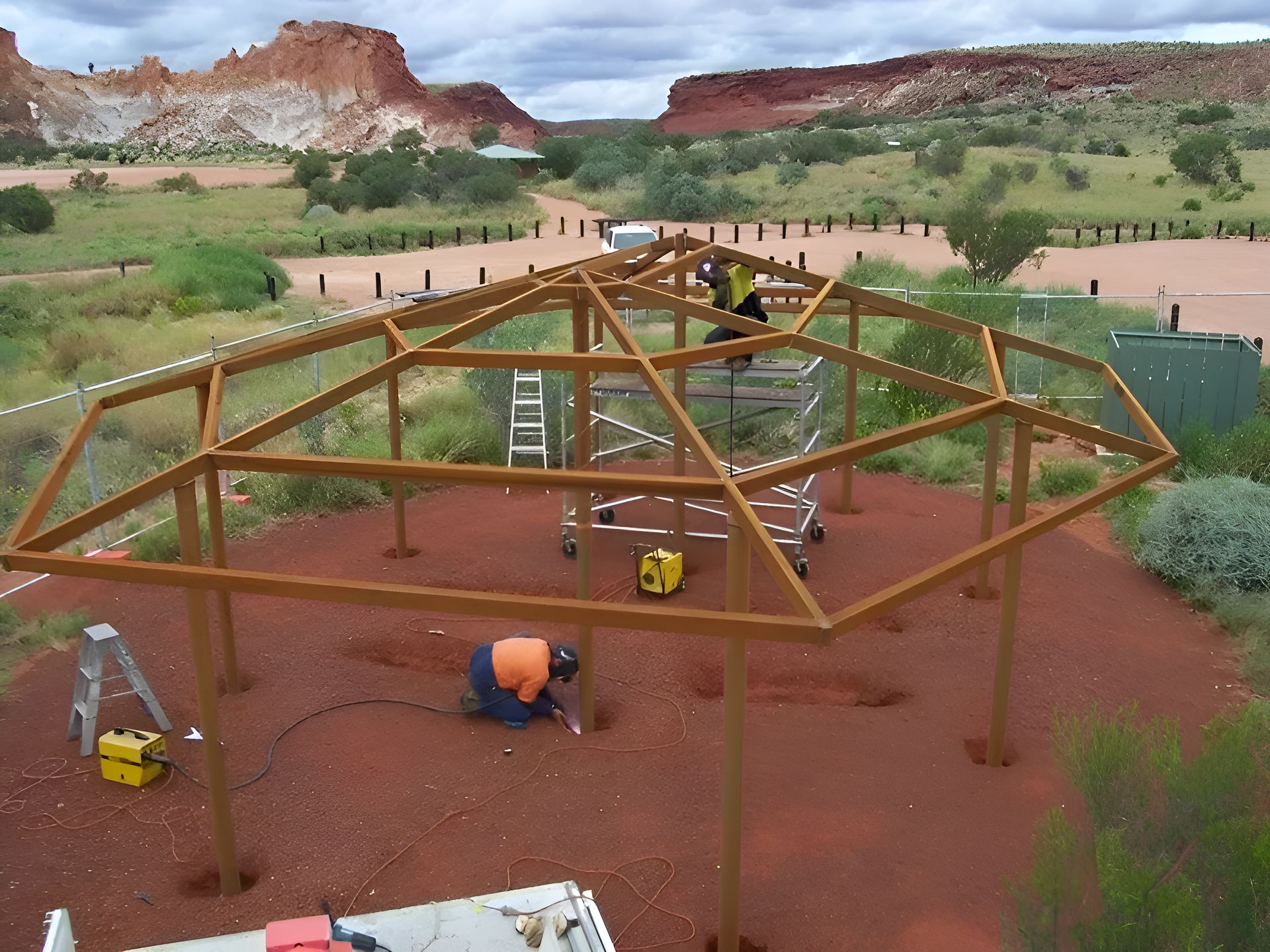 A Man Is Working On A Wooden Structure In The Desert — Sno's Welding In Ciccone, NT