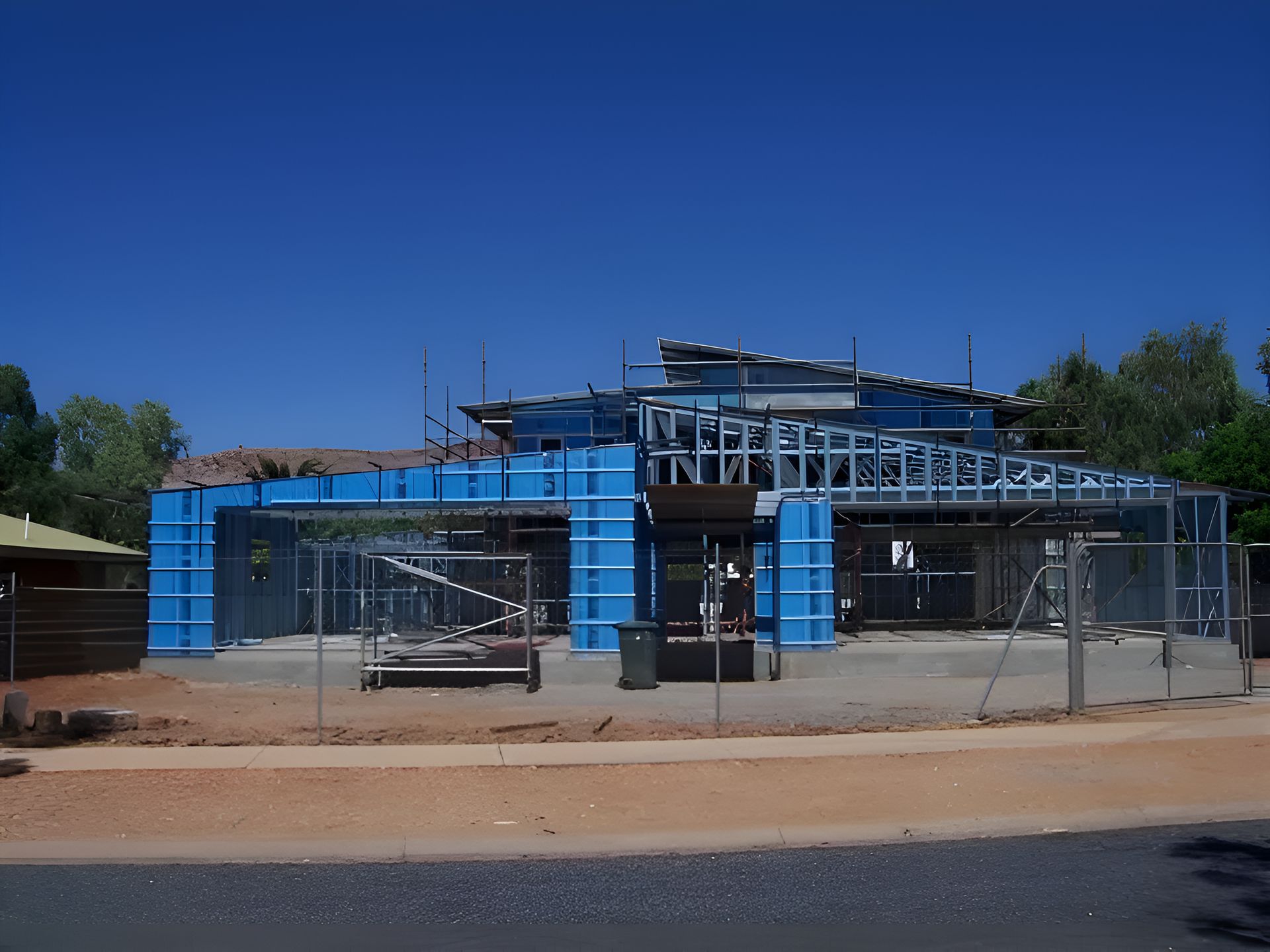 A Building Under Construction With A Blue Fence Around It — Sno's Welding In Ciccone, NT
