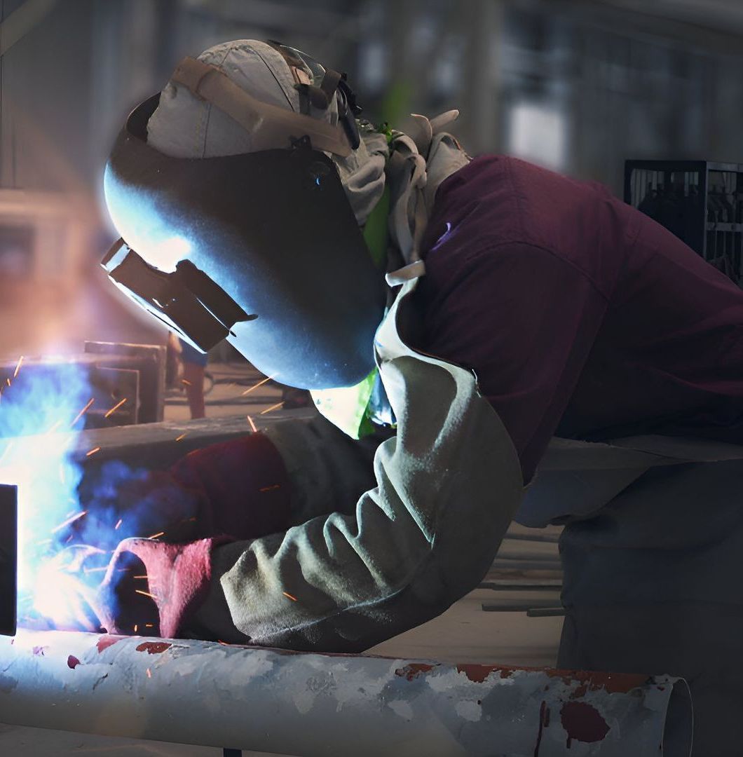 A Man Wearing A Welding Mask Is Welding A Pipe — Sno's Welding In Ciccone, NT