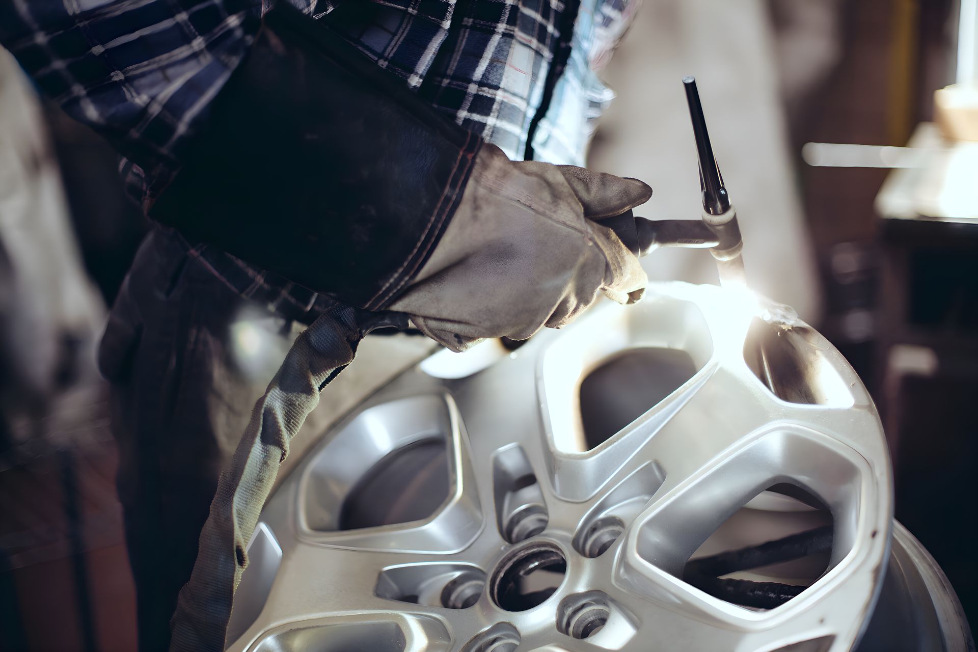 A Man Is Welding A Car Wheel In A Garage — Sno's Welding In Ciccone, NT