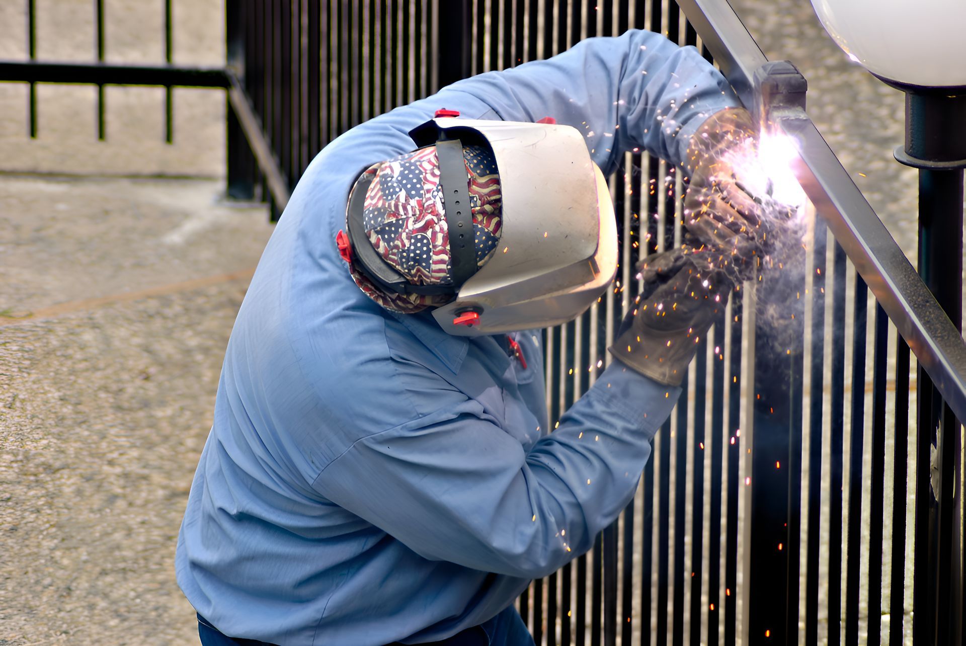A Man Wearing A Welding Mask Is Welding A Fence — Sno's Welding In Ciccone, NT