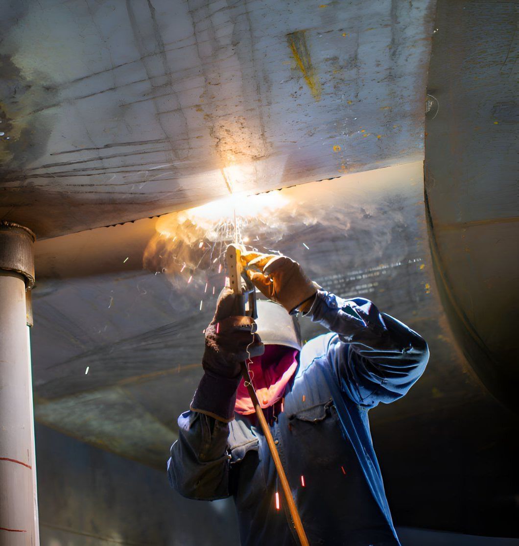 A Man Is Welding A Pipe In A Dark Room — Sno's Welding In Ciccone, NT
