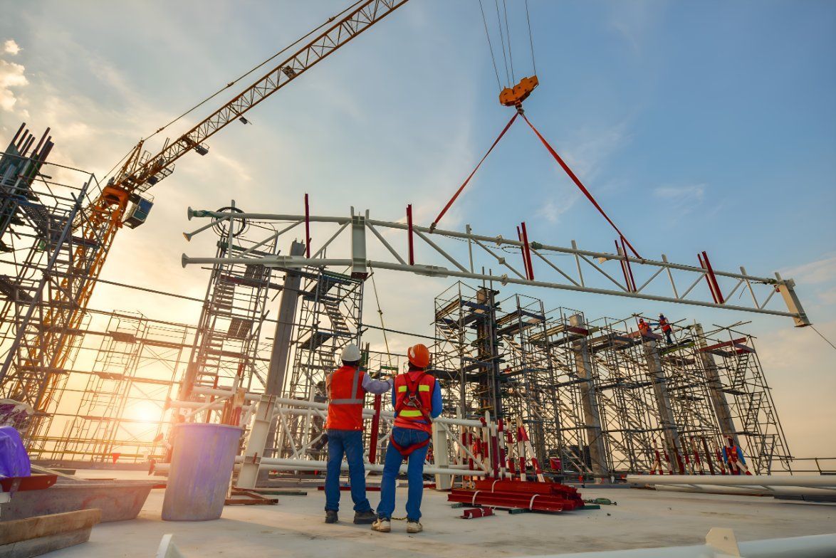 Two Construction Workers Are Standing In Front Of A Building Under Construction — Sno's Welding In Ciccone, NT