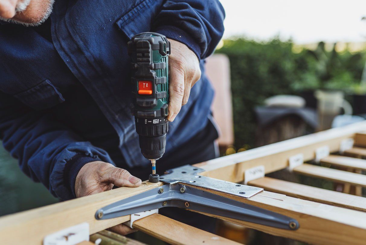 Man with a drill screwing into a wood — Harker Heights, TX — Kuality Landscaping & Handyman Services LLC