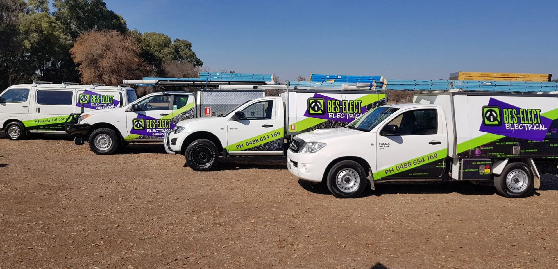 Three White Service Trucks with Green Purple Logos Parked on A Dirt Lot — Bes-Elect Electrical in Taminda, NSW
