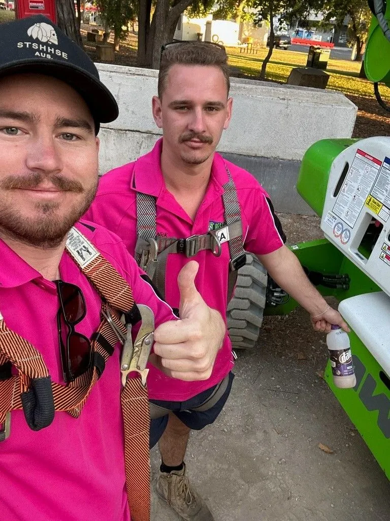 Two men in pink shirts at an outdoor event, one giving a thumbs-up — Bes-Elect Electrical in Taminda, NSW
