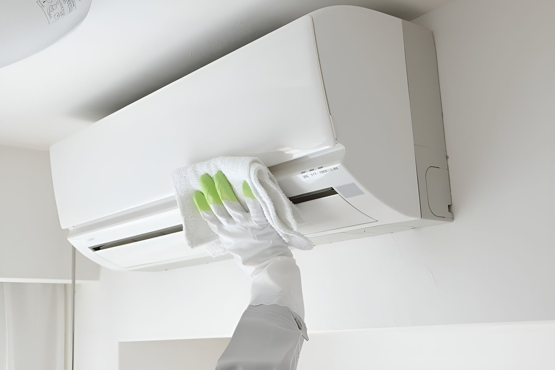 Gloved Hand Cleaning a White Wall Mounted Air Conditioner Filter — Bes-Elect Electrical in Taminda, NSW