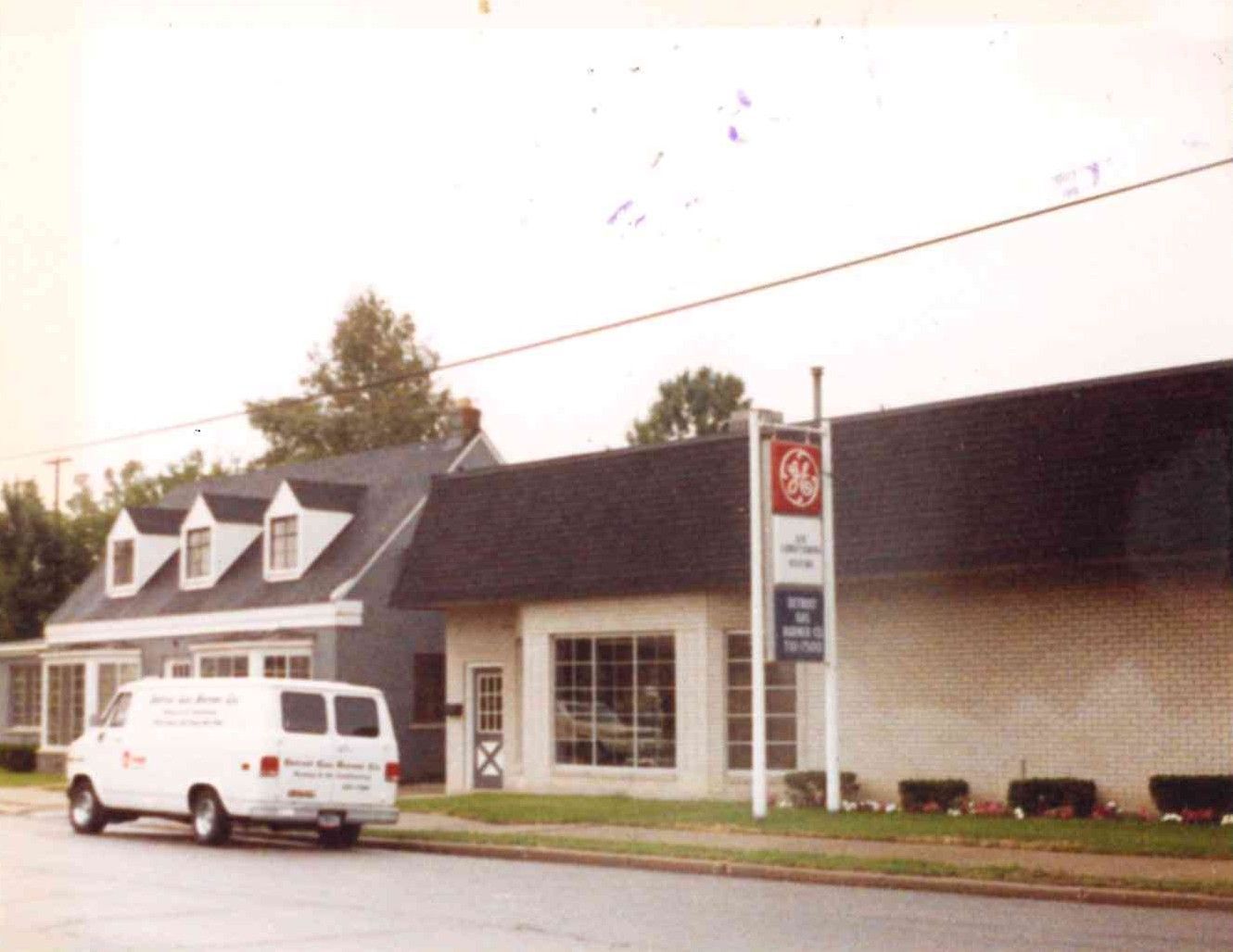 White van parked outside a beige storefront with a dark roof and gas station sign.