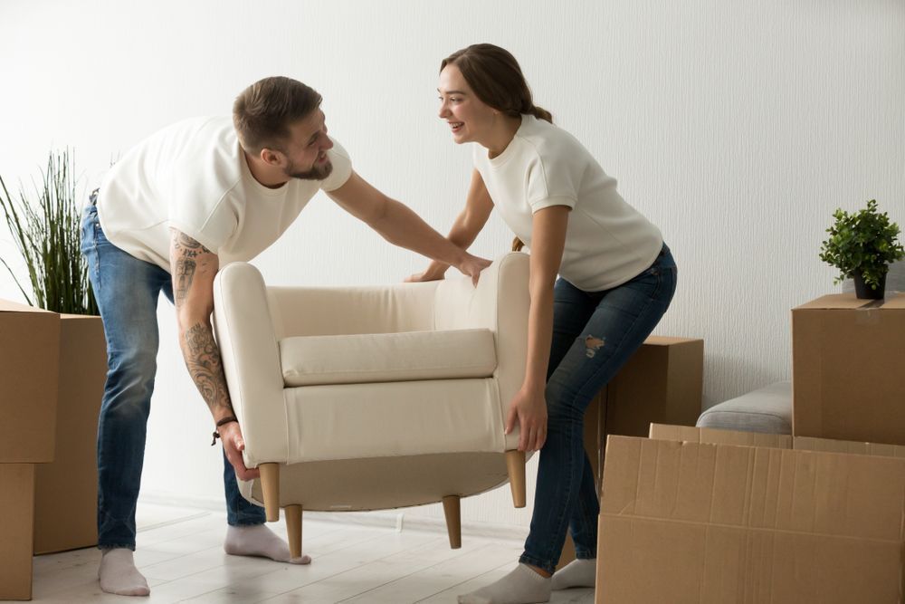 A man and a woman are lifting a chair in a living room — South Burnett Truck Rental In Kingaroy, Qld