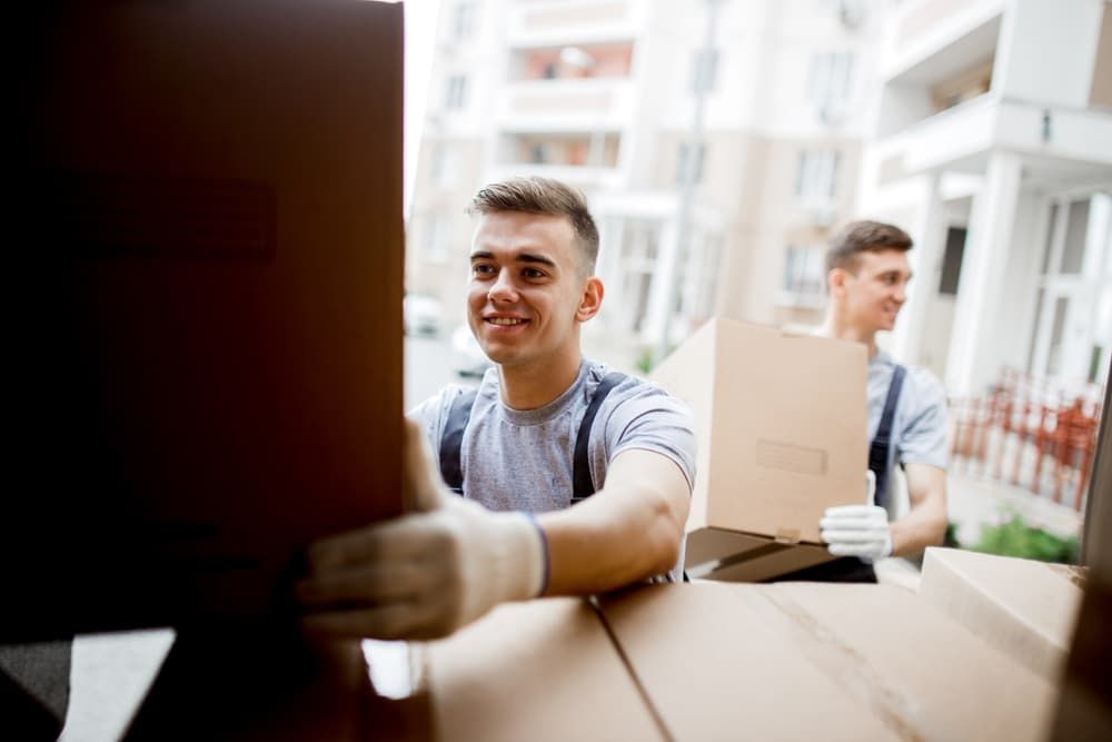 A Man Is Holding A Cardboard Box In His Hand — South Burnett Truck Rental In Kingaroy, QLD