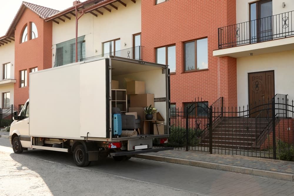 A Moving Truck Is Parked In Front Of A Brick Building — South Burnett Truck Rental In Gayndah, QLD