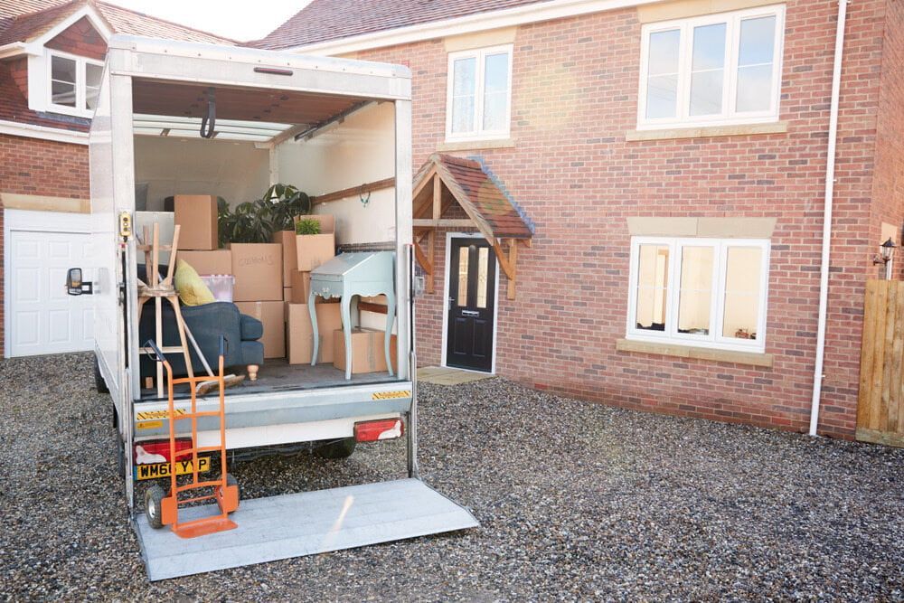 A Moving Truck Is Parked In Front Of A Brick House — South Burnett Truck Rental In Maryborough, QLD