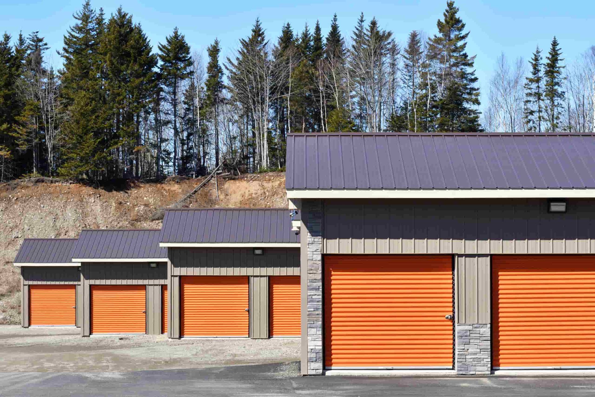 A Row Of Garages With Orange Doors And Trees In The Background — South Burnett Truck Rental In Tara, QLD