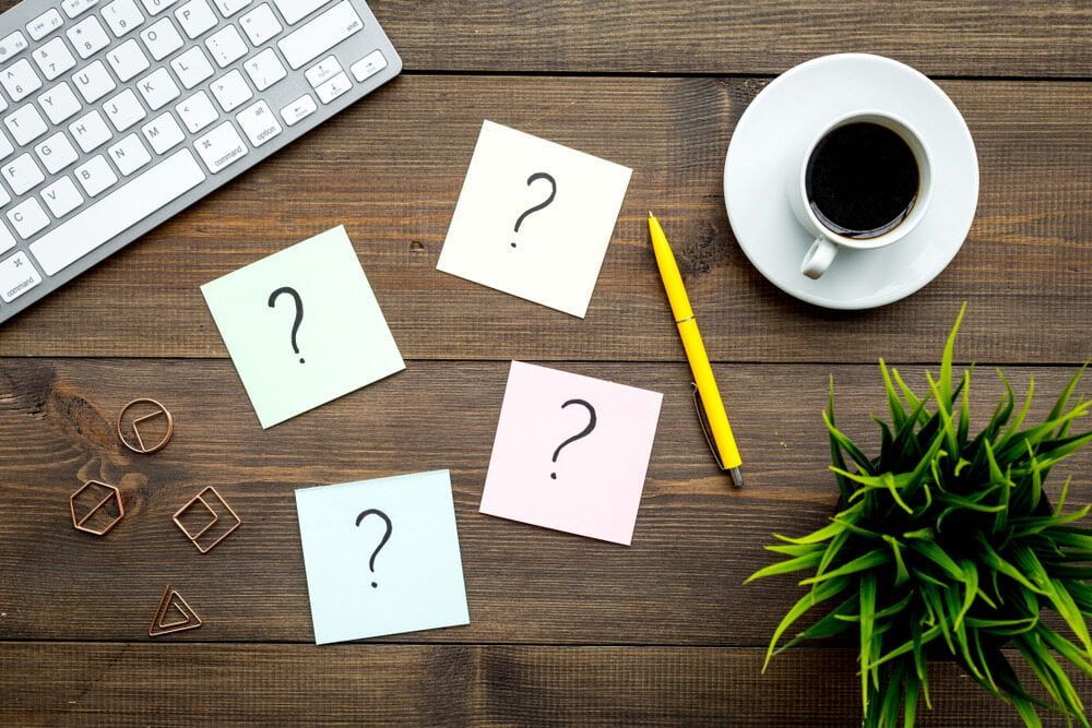 Wooden Desk With Question Marks Notes, A Coffee, A Pen, And A Keyboard — South Burnett Truck Rental In Maryborough, QLD