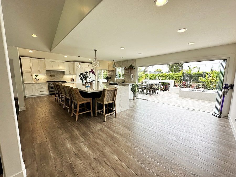 Open-plan kitchen and dining area with wood floors, island seating, and a large open patio view