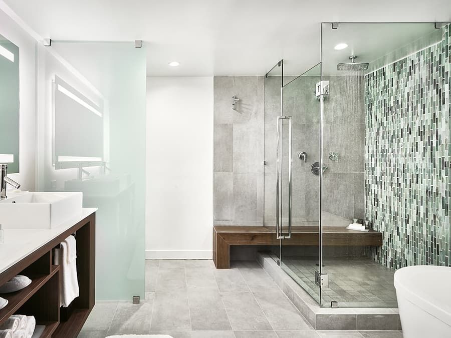 Modern bathroom with glass shower enclosure, vanity, and gray tile accents