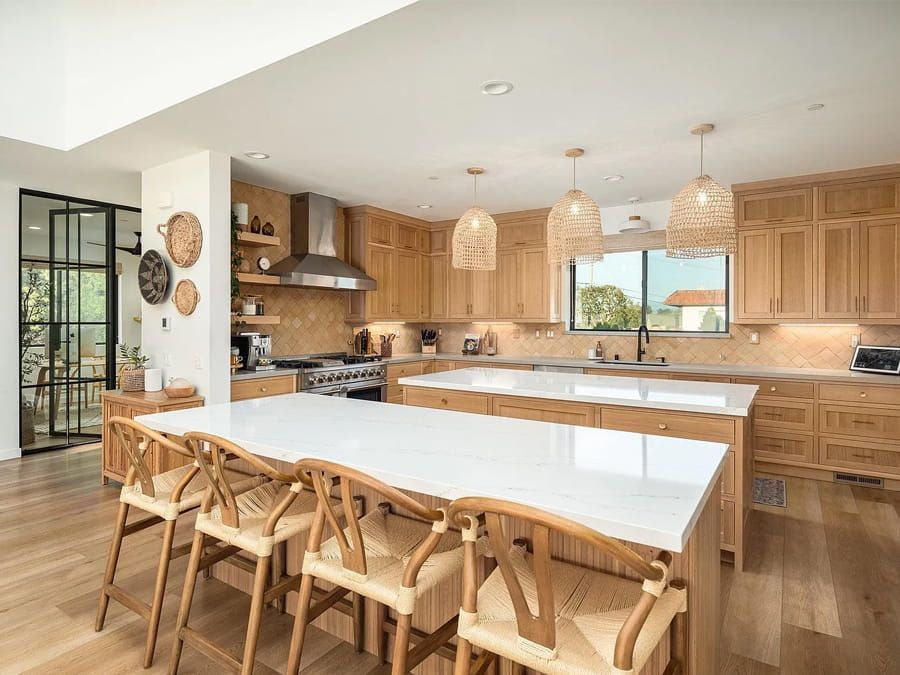 Bright modern kitchen with wood cabinets, island seating, and a large dining table by the windows