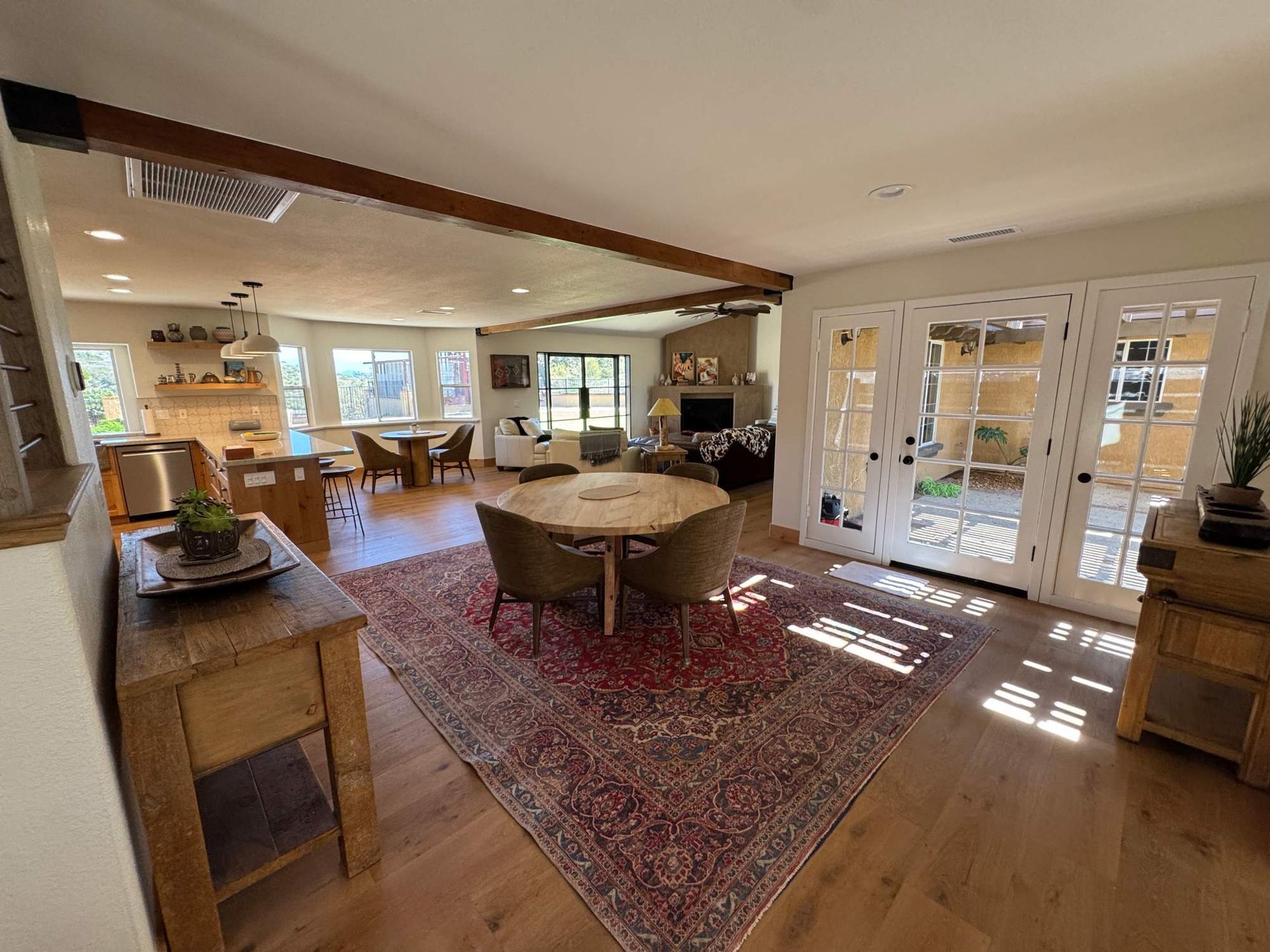 Spacious living room with a red rug, sectional sofa, and French doors opening to a bright patio.