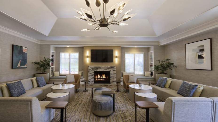 Elegant living room with symmetrical sofas, round tables, fireplace, and modern chandelier
