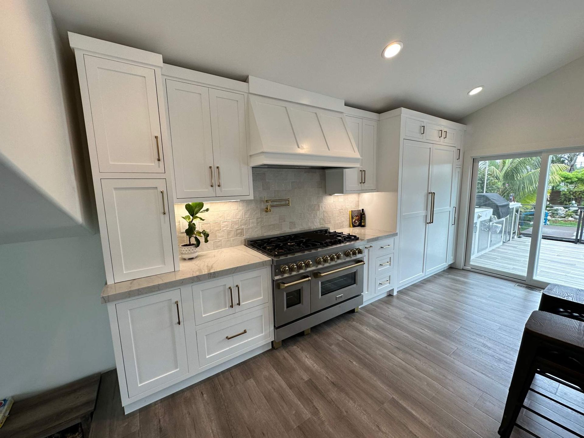 Bright white modern kitchen with gas range, island counter, and sliding glass doors to a patio