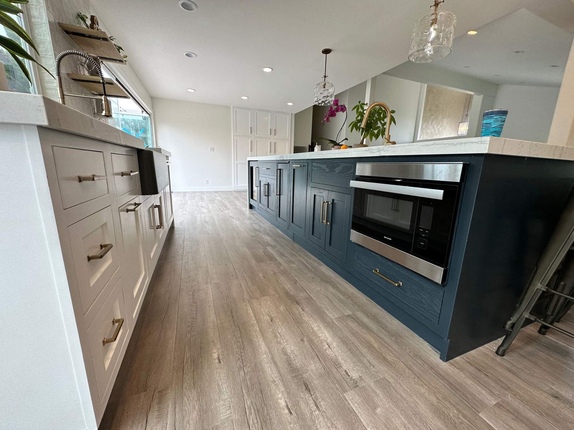 Modern kitchen with dark island cabinetry, built-in oven, wood flooring, and bright open layout