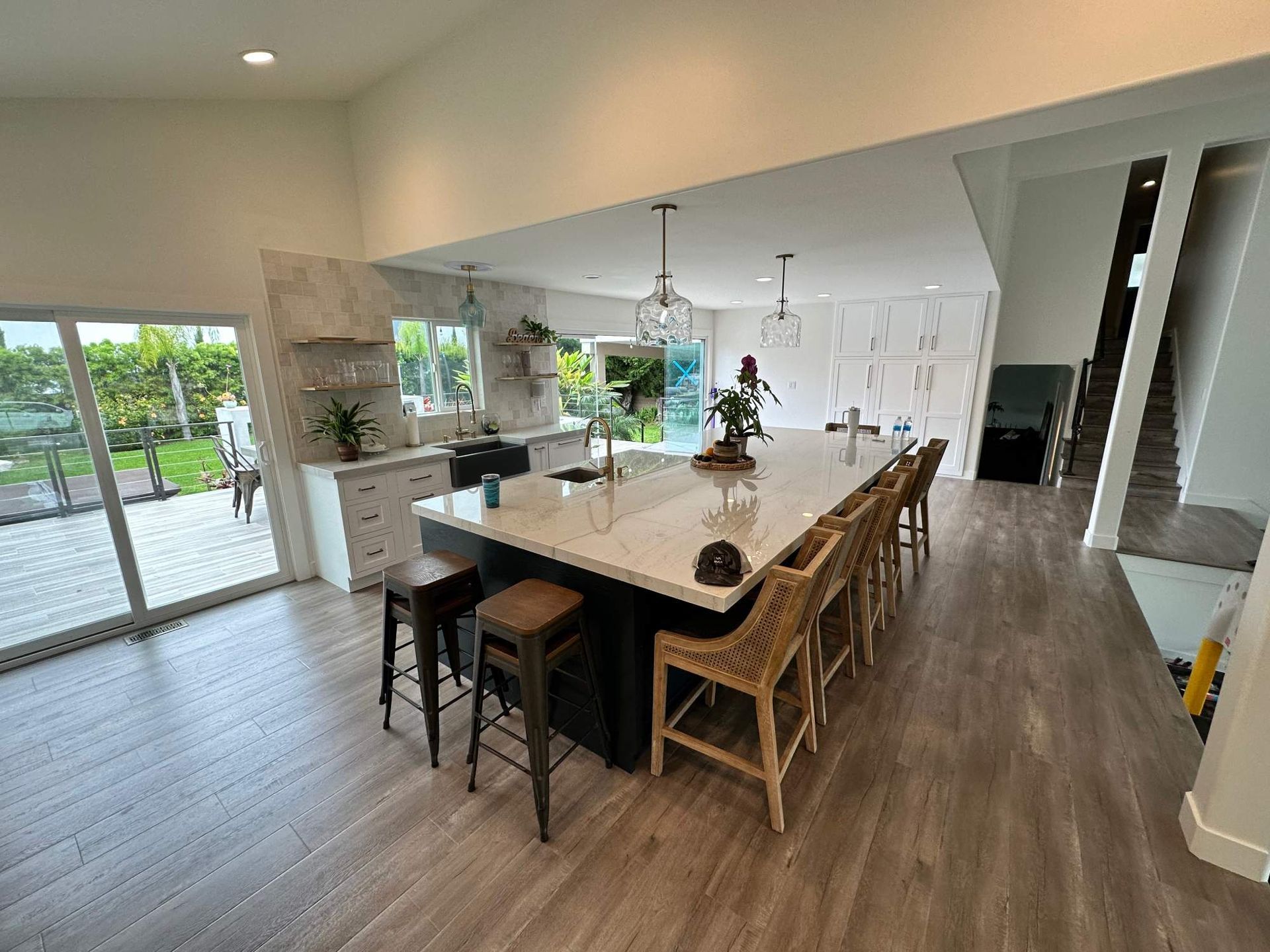 Modern kitchen with a long island, bar stools, and bright sliding glass doors to a patio