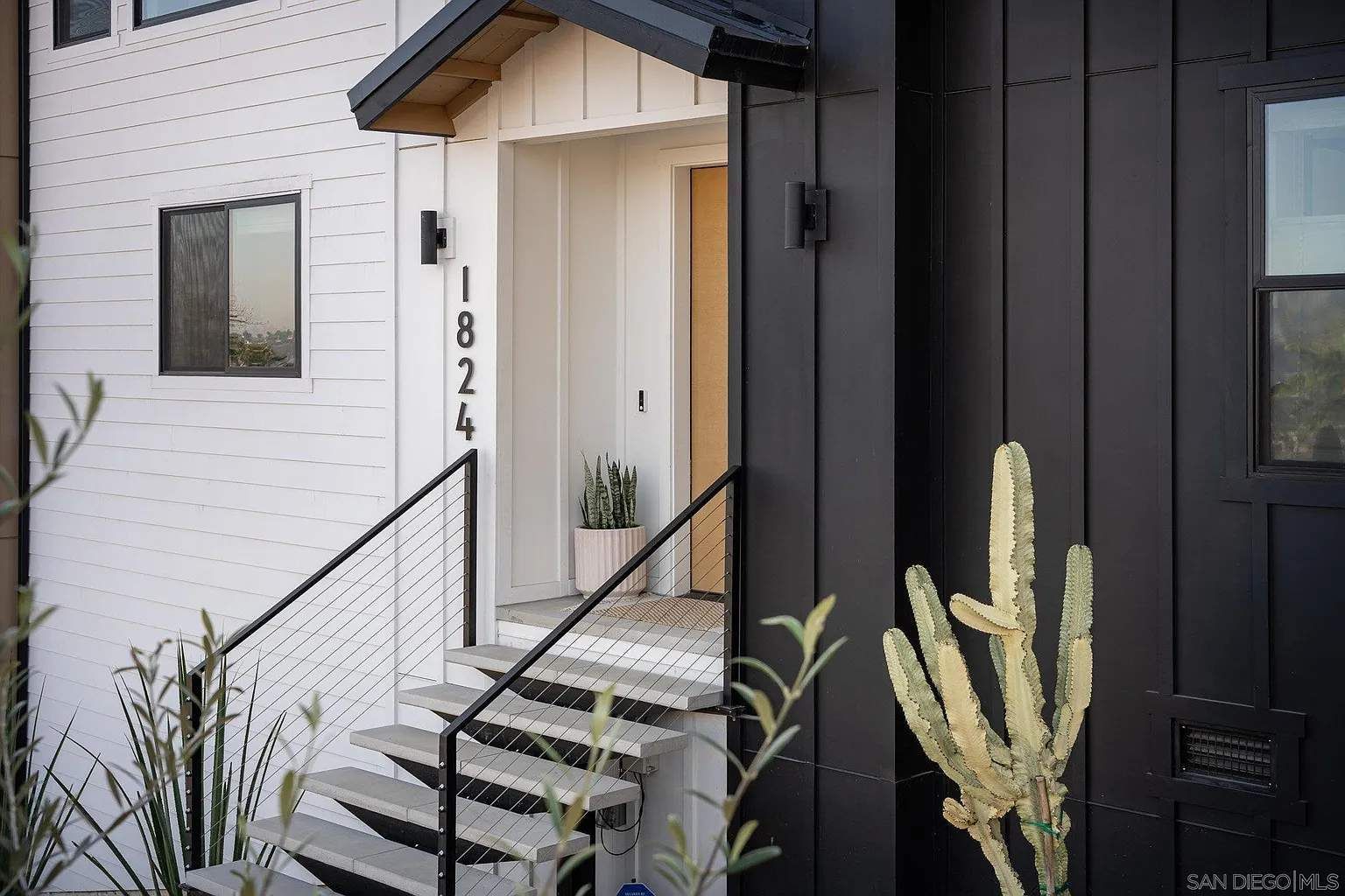 Modern townhouse entrance with white brick, black trim, stairs, and house number 8424.