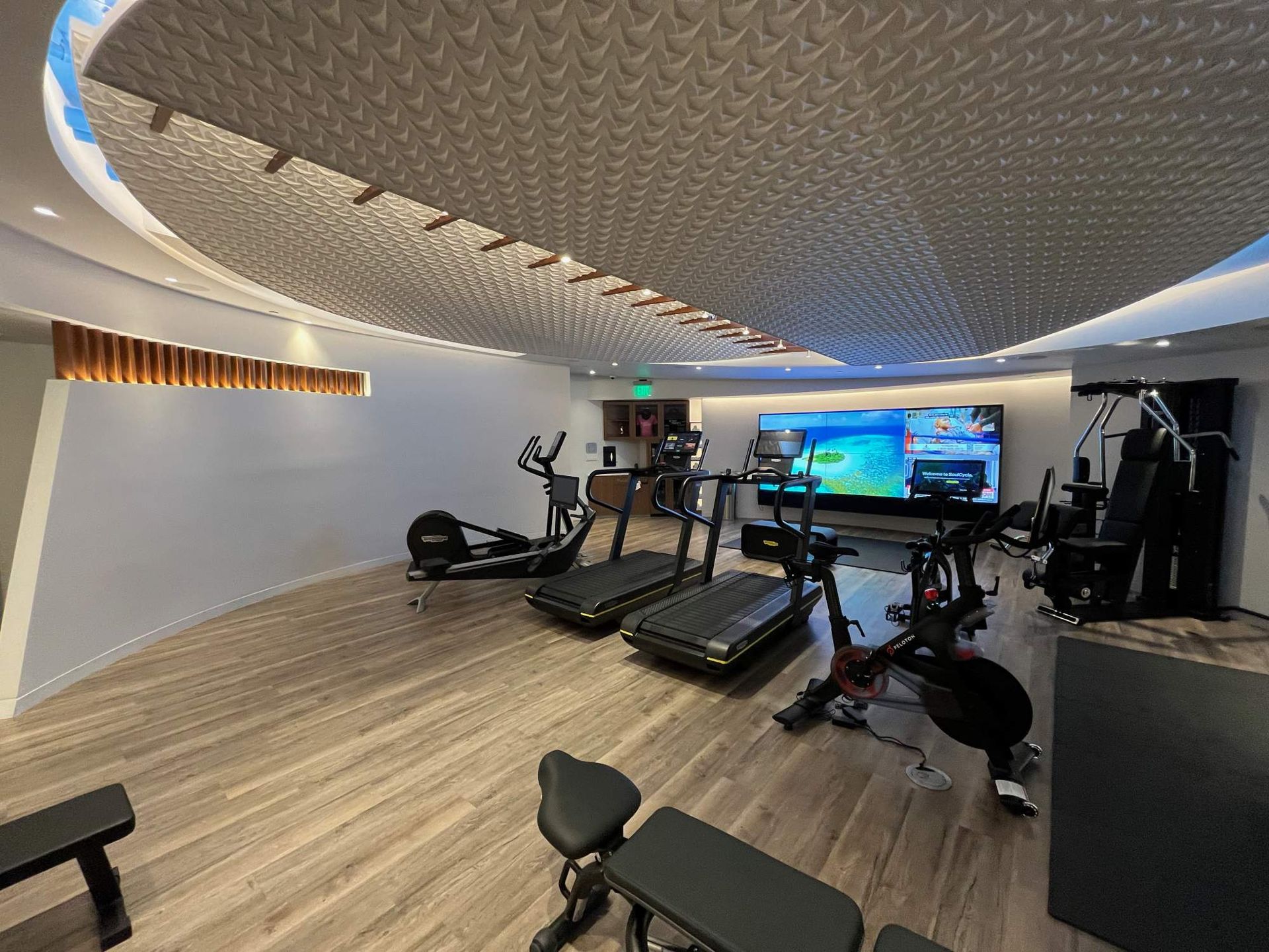 Modern gym with treadmills, exercise bikes, and strength equipment under a curved ceiling
