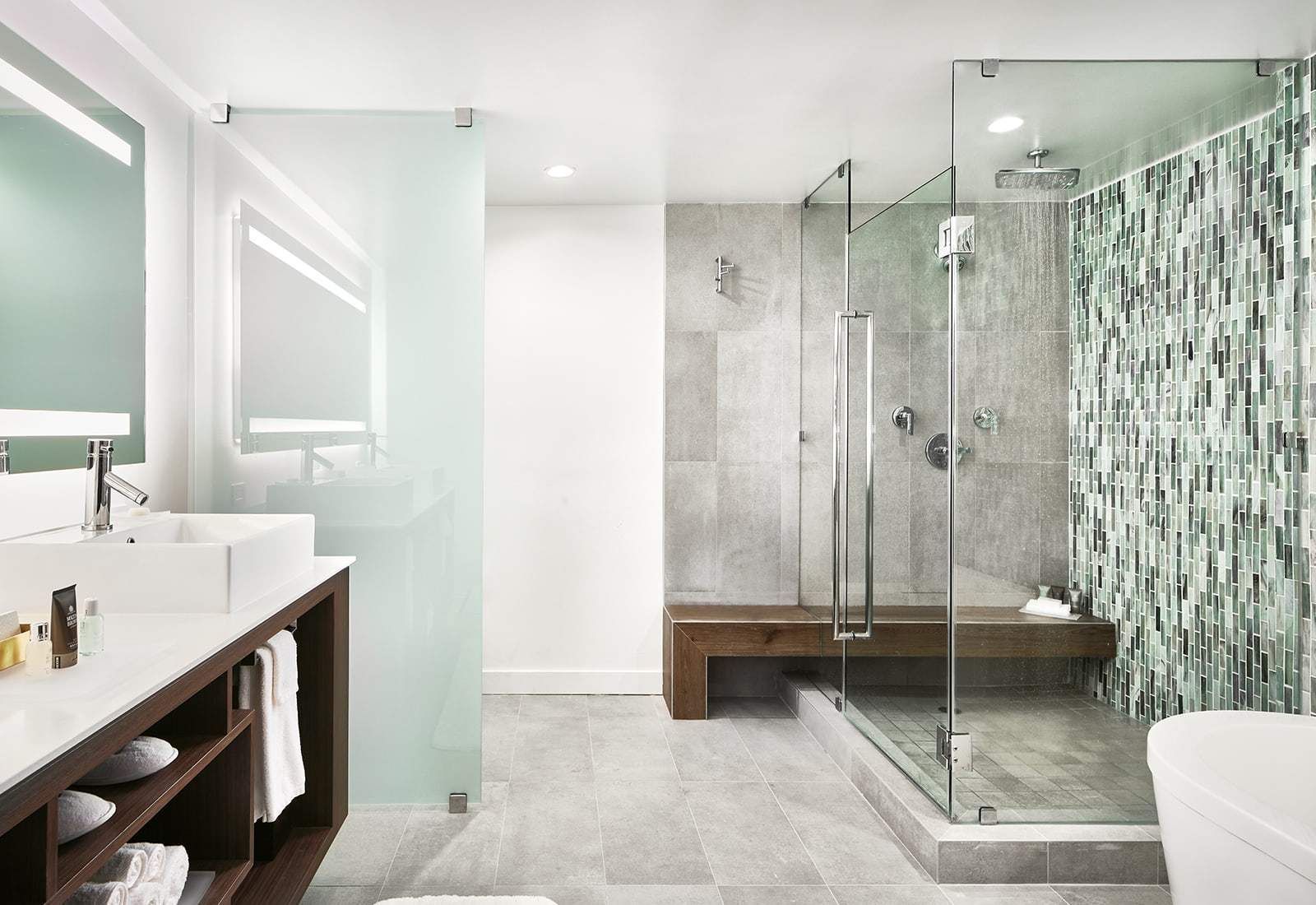 Modern bathroom with white vanity, glass shower, gray tile, and green mosaic accent wall