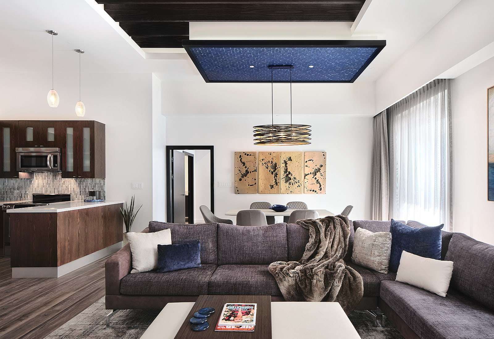 Modern living room with dark sectional sofa, central coffee table, fireplace, and blue-lit ceiling inset