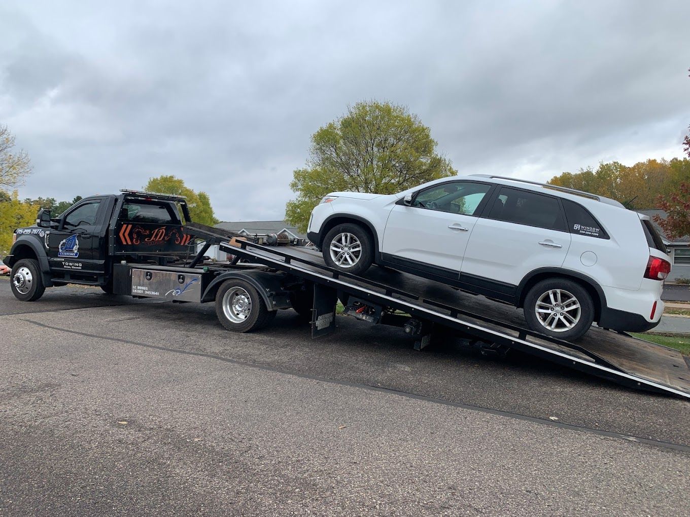 A white suv is being towed by a tow truck.