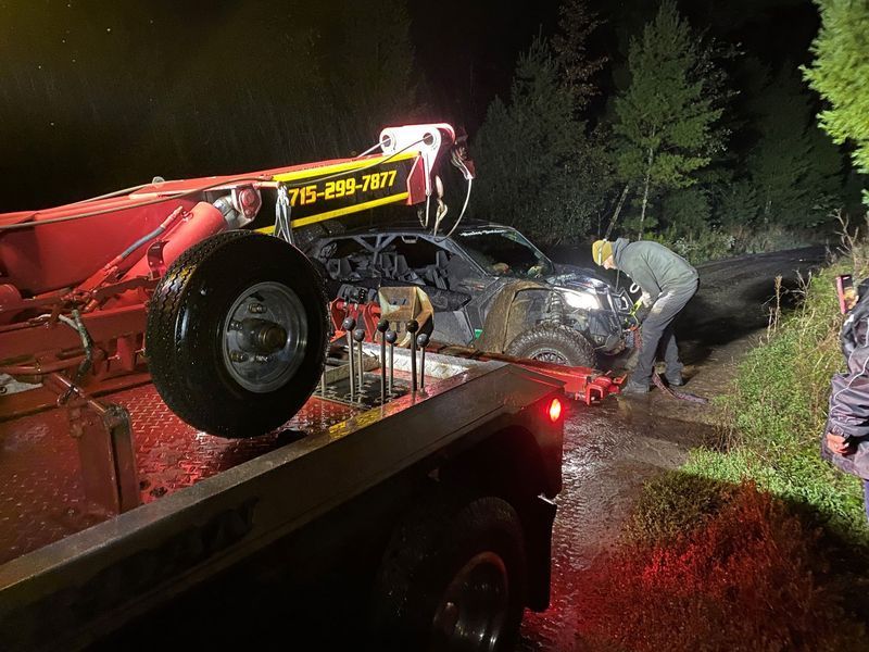 A car is being towed by a tow truck at night.